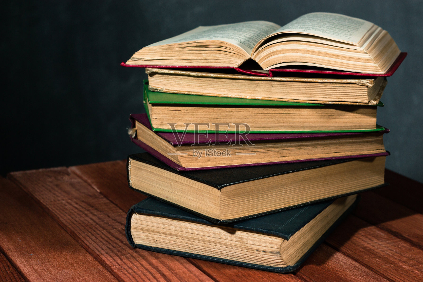 旧书放在一张红色的木头桌子上。美丽的黑色背景。照片摄影图片