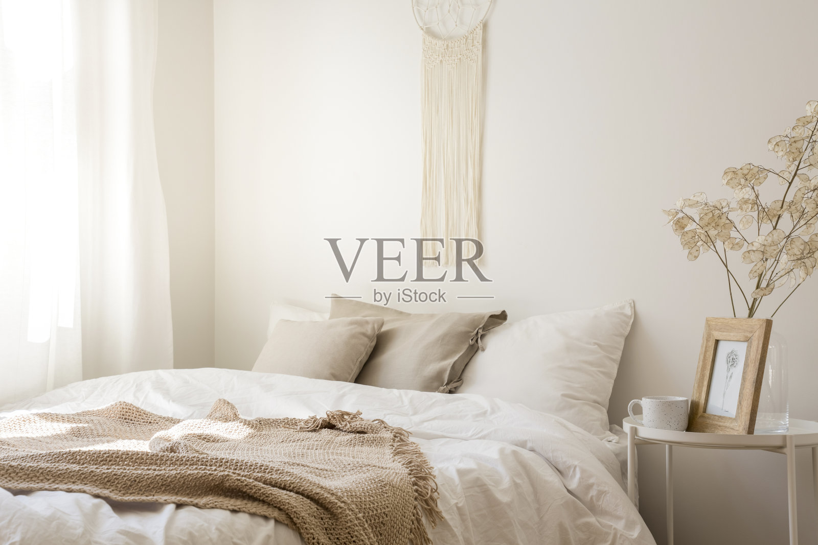 上面的流苏舒适的大床，白色的床上用品，米色的枕头和毯子，真实的照片照片摄影图片