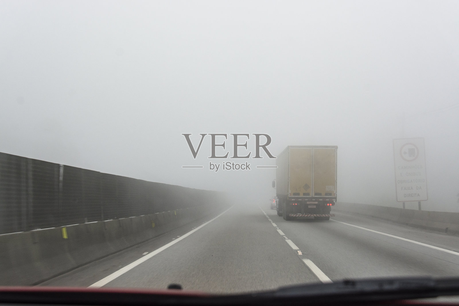 一辆卡车在浓雾中在双车道上超车。照片摄影图片