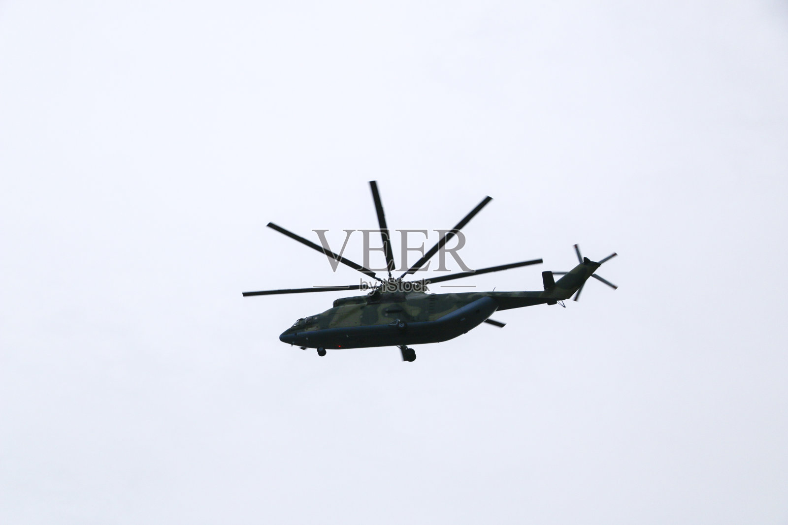 一架大型军用直升机在空中盘旋。一架伪装直升机高速飞行。照片摄影图片