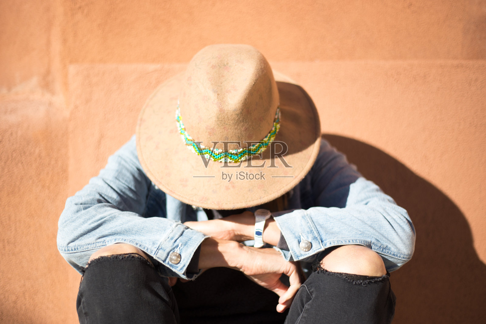 独自垂头坐着的女人；橙色背景照片摄影图片