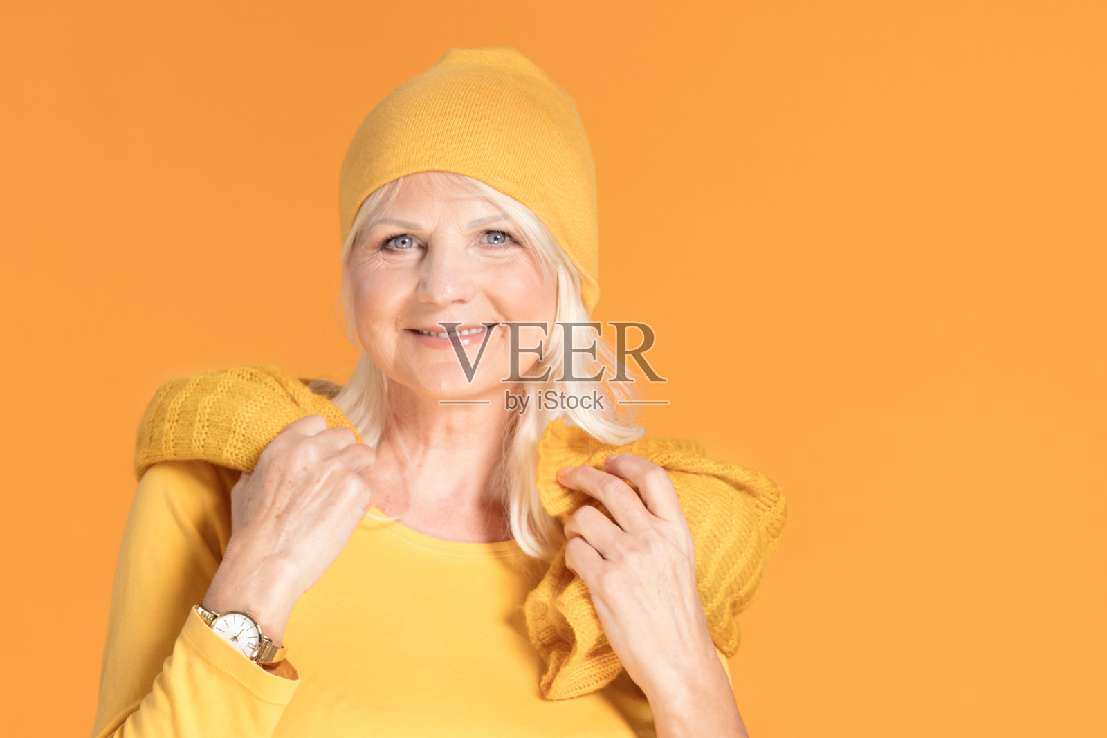 年长妇女摆姿势戴着帽子和围巾。照片摄影图片