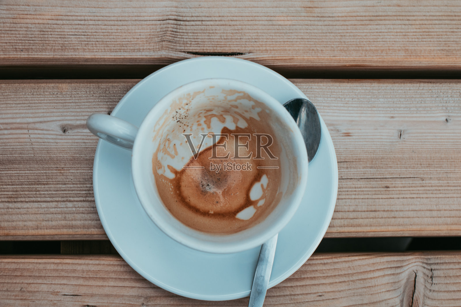 消费-空卡布奇诺杯和勺子在咖啡馆的咖啡桌上照片摄影图片