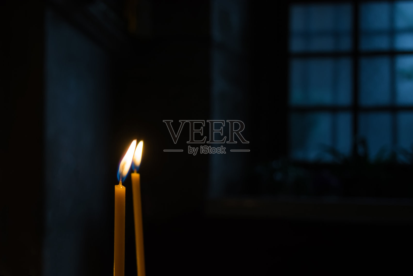 在黑暗的房间里，对着窗户燃烧着蜡烛照片摄影图片