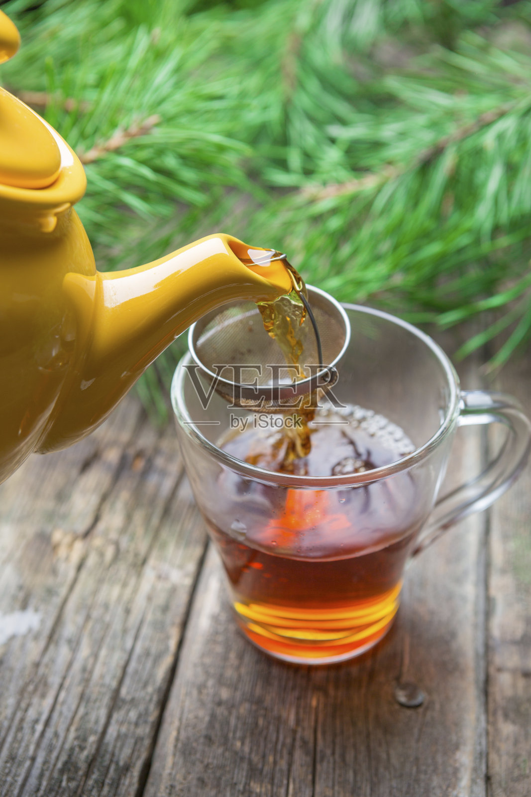 黄茶壶在木桌上的玻璃杯里倒红茶照片摄影图片