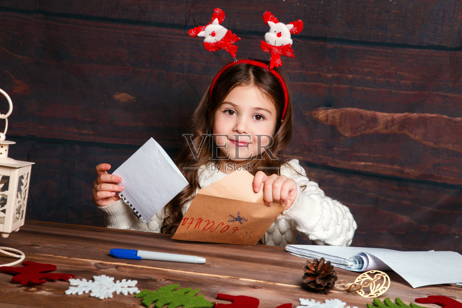 孩子给圣诞老人写信。滑稽的女孩戴着圣诞帽给圣诞老人写信照片摄影图片