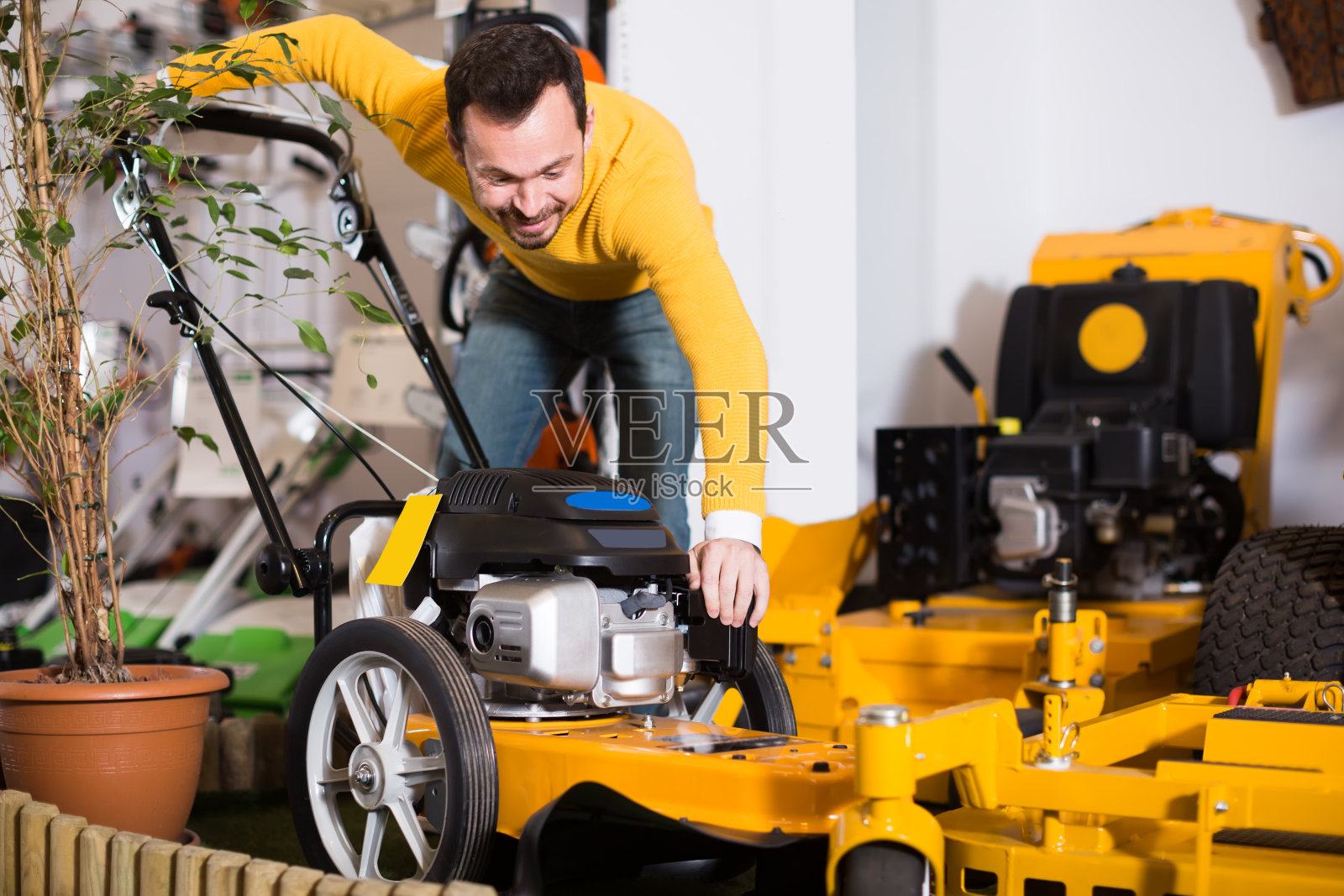 快乐的男人决定在园艺设备店买最好的割草机照片摄影图片