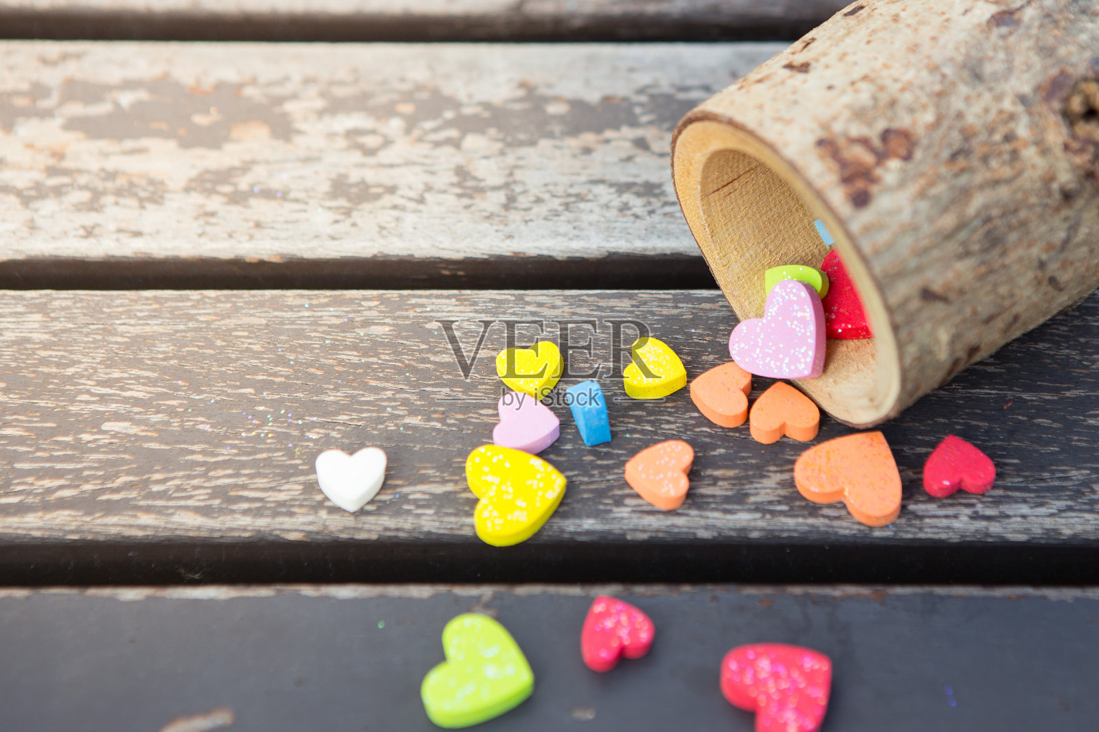 许多五颜六色的小心脏放在一个旧木桌上，以阳光和自然为背景照片摄影图片