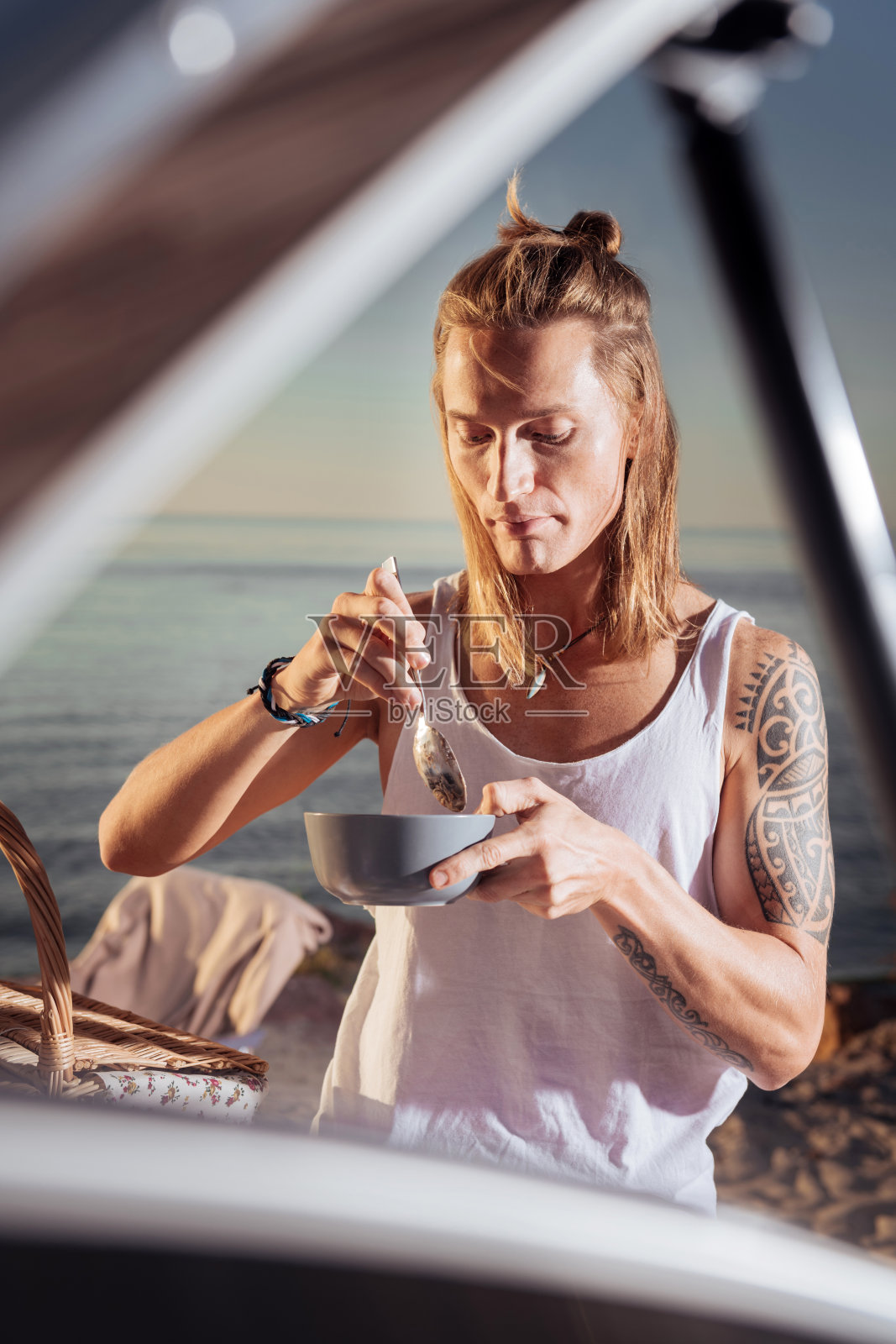 一个有着金色长发和纹身的男人在活动房附近吃早餐照片摄影图片