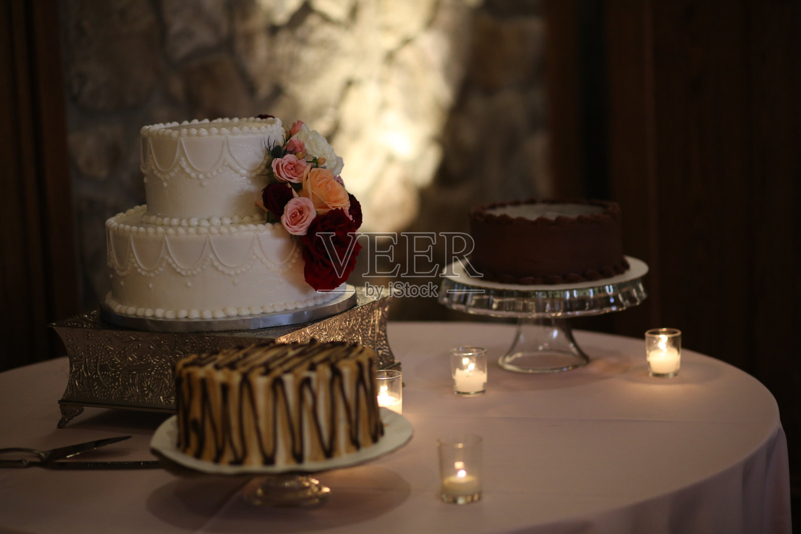 奶油婚礼蛋糕装饰白色，粉红色，和红色玫瑰在一个银色蛋糕架照片摄影图片