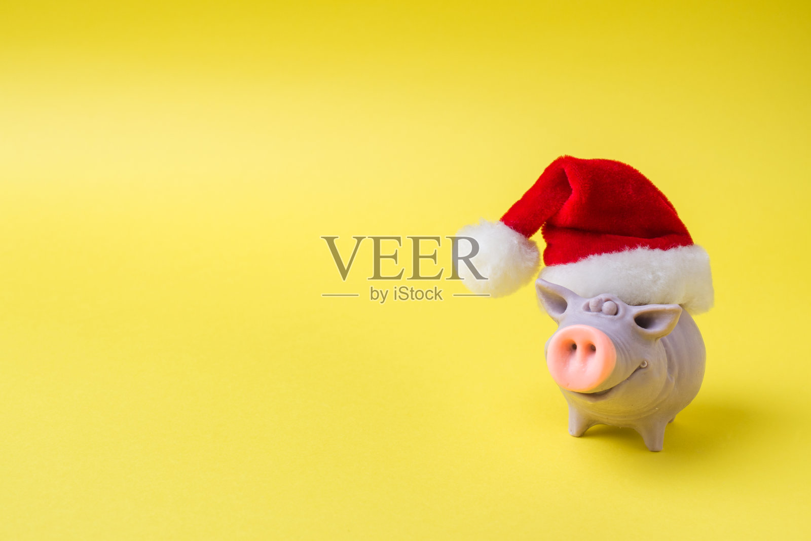 圣诞节和新年的概念。黄色背景上戴着圣诞帽的猪的形象。本空间照片摄影图片