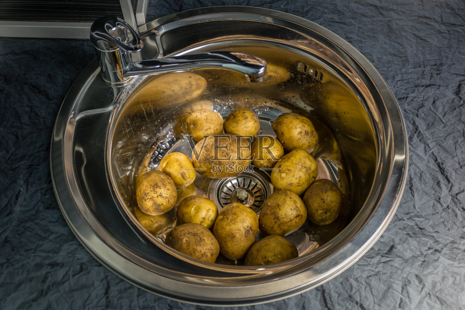 把生土豆洗一洗。象征着农村家庭烹饪和园艺。健康食品的生活方式。照片摄影图片