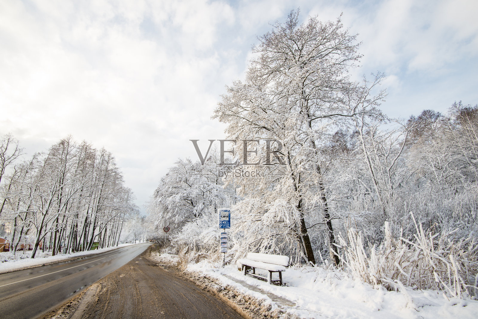 一辆公共汽车停在穿过拉脱维亚森林的积雪覆盖的乡村公路上照片摄影图片