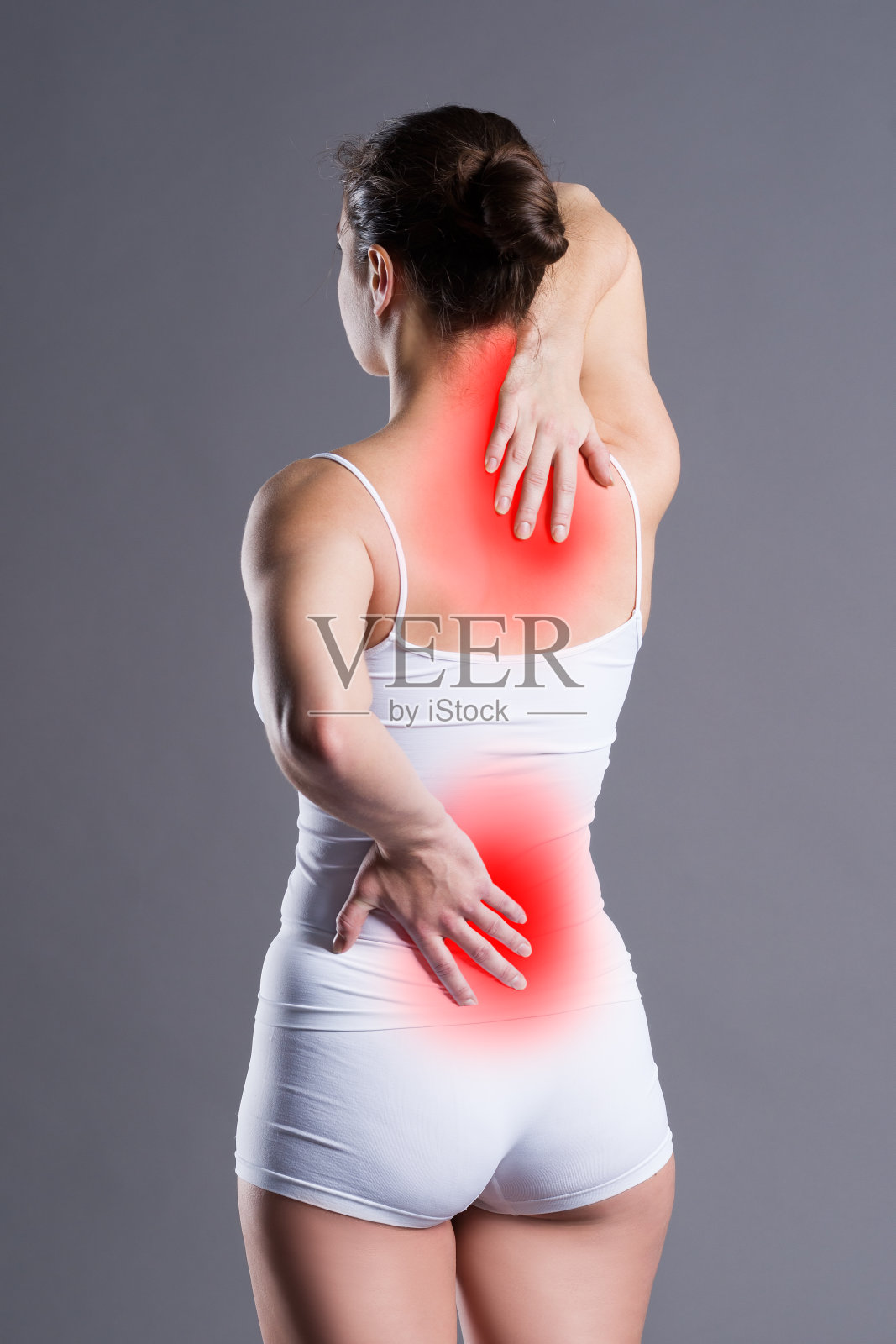 背部疼痛，灰色背景下背部疼痛的女人，在摄影棚拍摄照片摄影图片