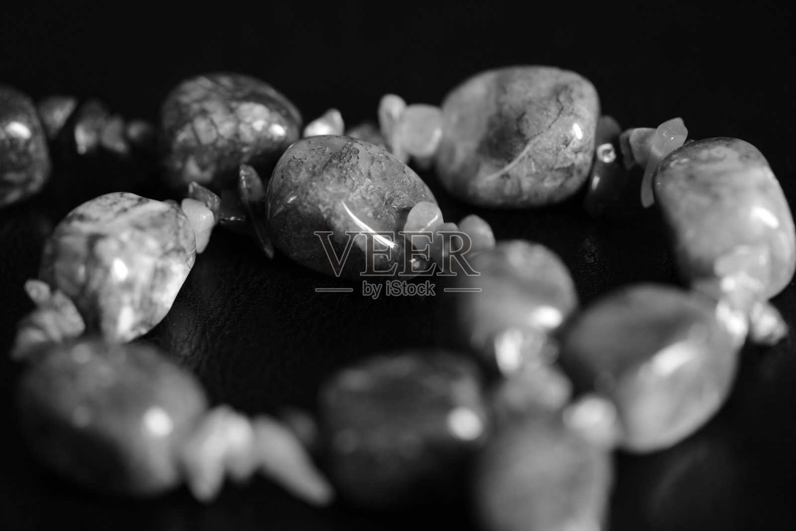 一条项链的碎片从一个天然的石头在一个黑暗的背景近距离。黑色和白色照片摄影图片