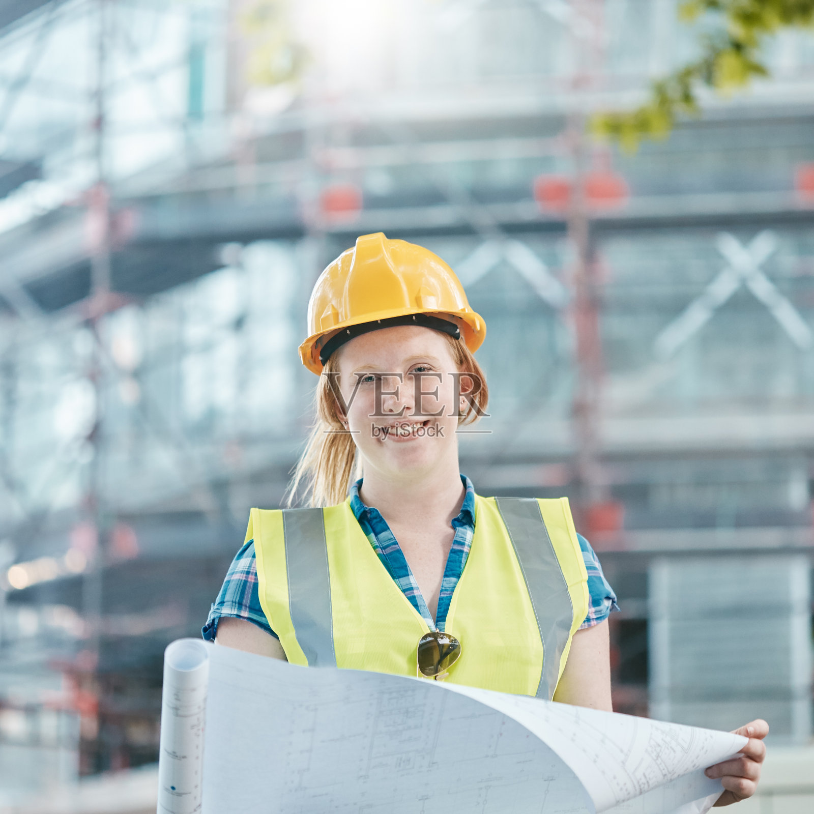 微笑的年轻女子建筑工人在现场举行计划照片摄影图片