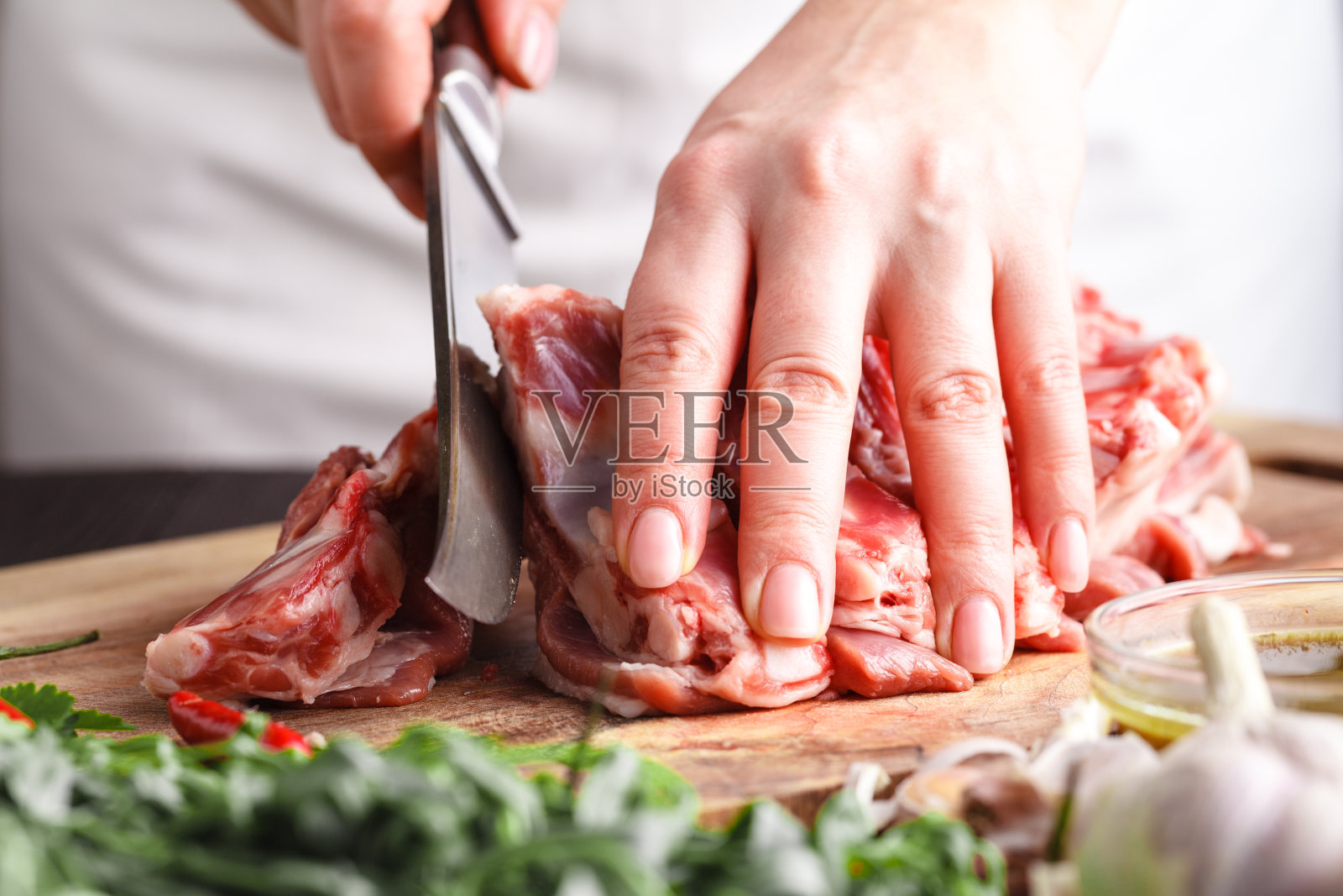 在餐厅厨房的木板上，一名男子正在切羊排。厨师正在为烹饪准备新鲜的肉照片摄影图片