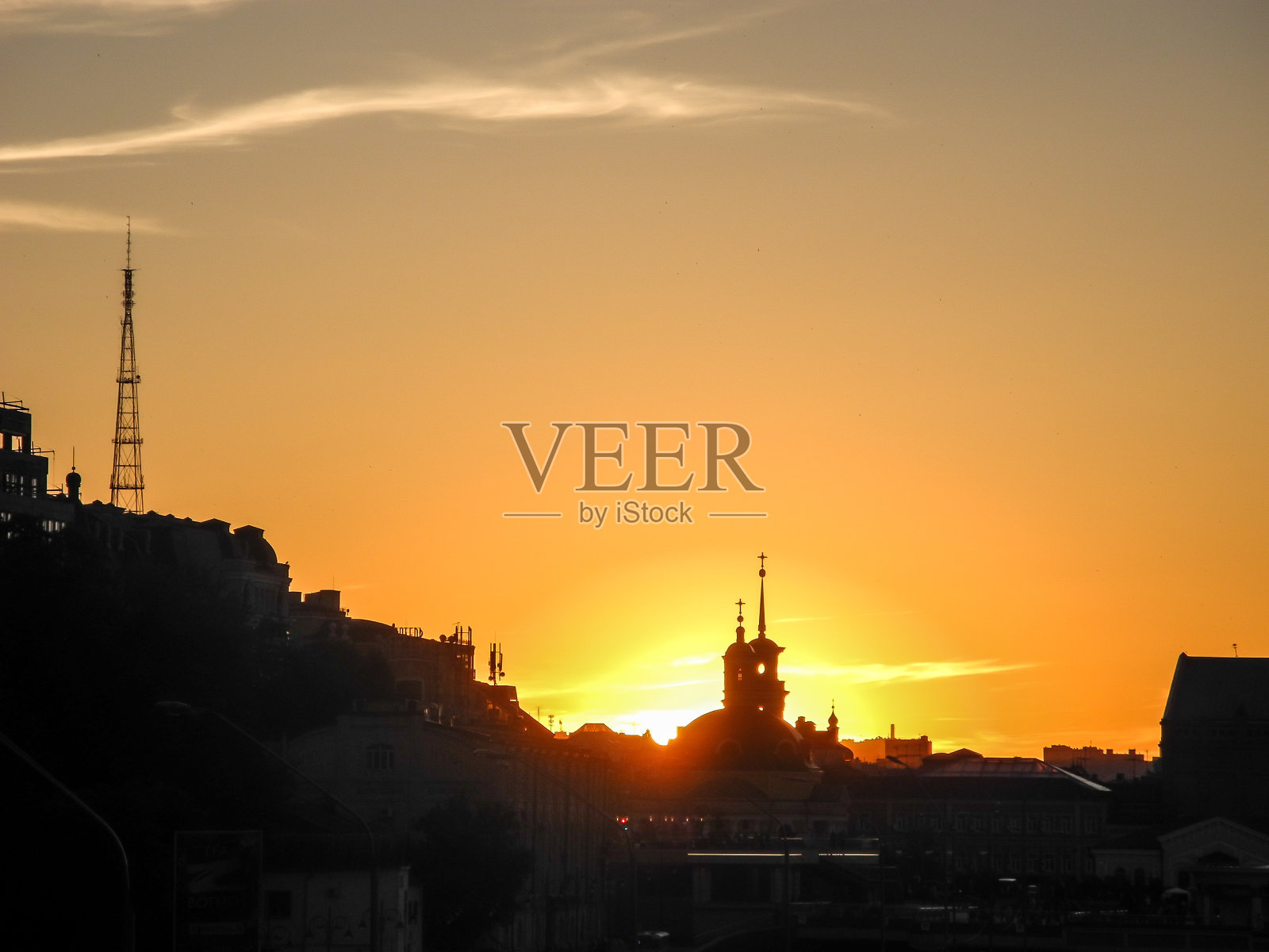 太阳藏在城市里教堂的圆顶后面。日落城市景观。照片摄影图片