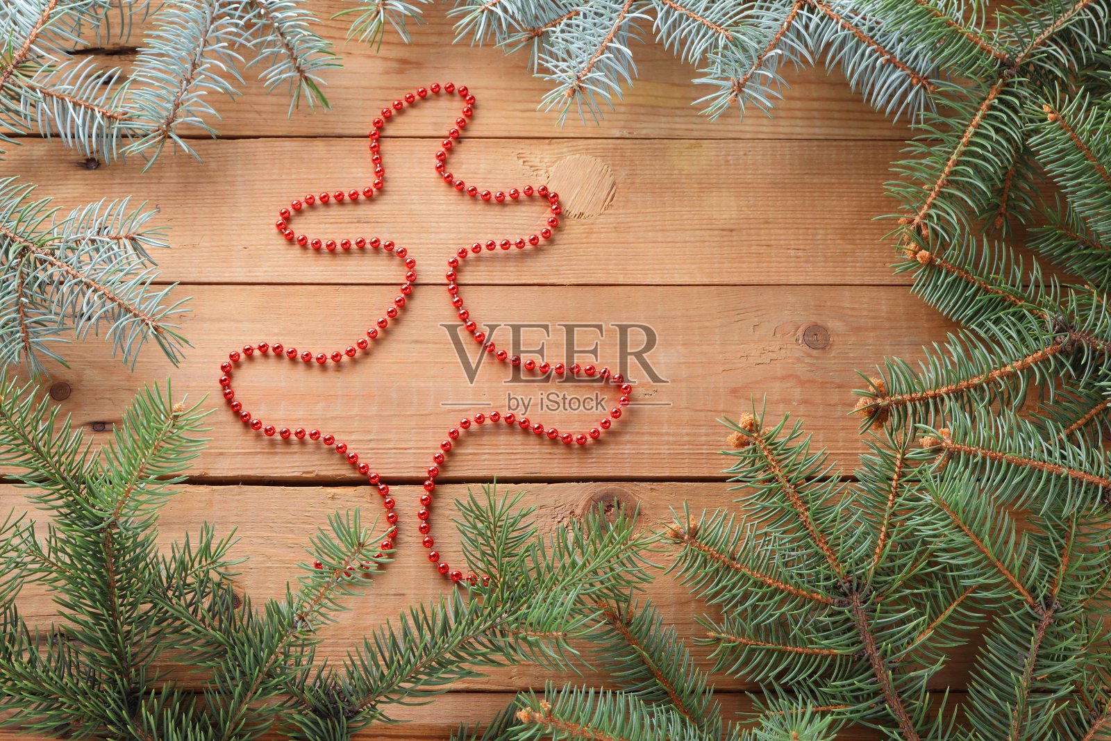 图的圣诞树从红色的项链。木板上的云杉树枝，俯视图。木制背景上的圣诞装饰。本空间照片摄影图片