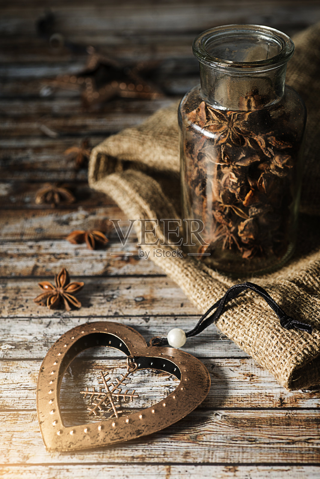 新的青铜玩具心和玻璃罐子和茴芹放在一个旧木头桌子上。乡村风格。照片摄影图片
