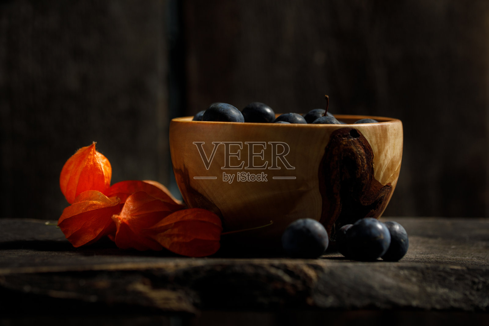 木碗里的李子。装饰从酸浆浆果。照片摄影图片