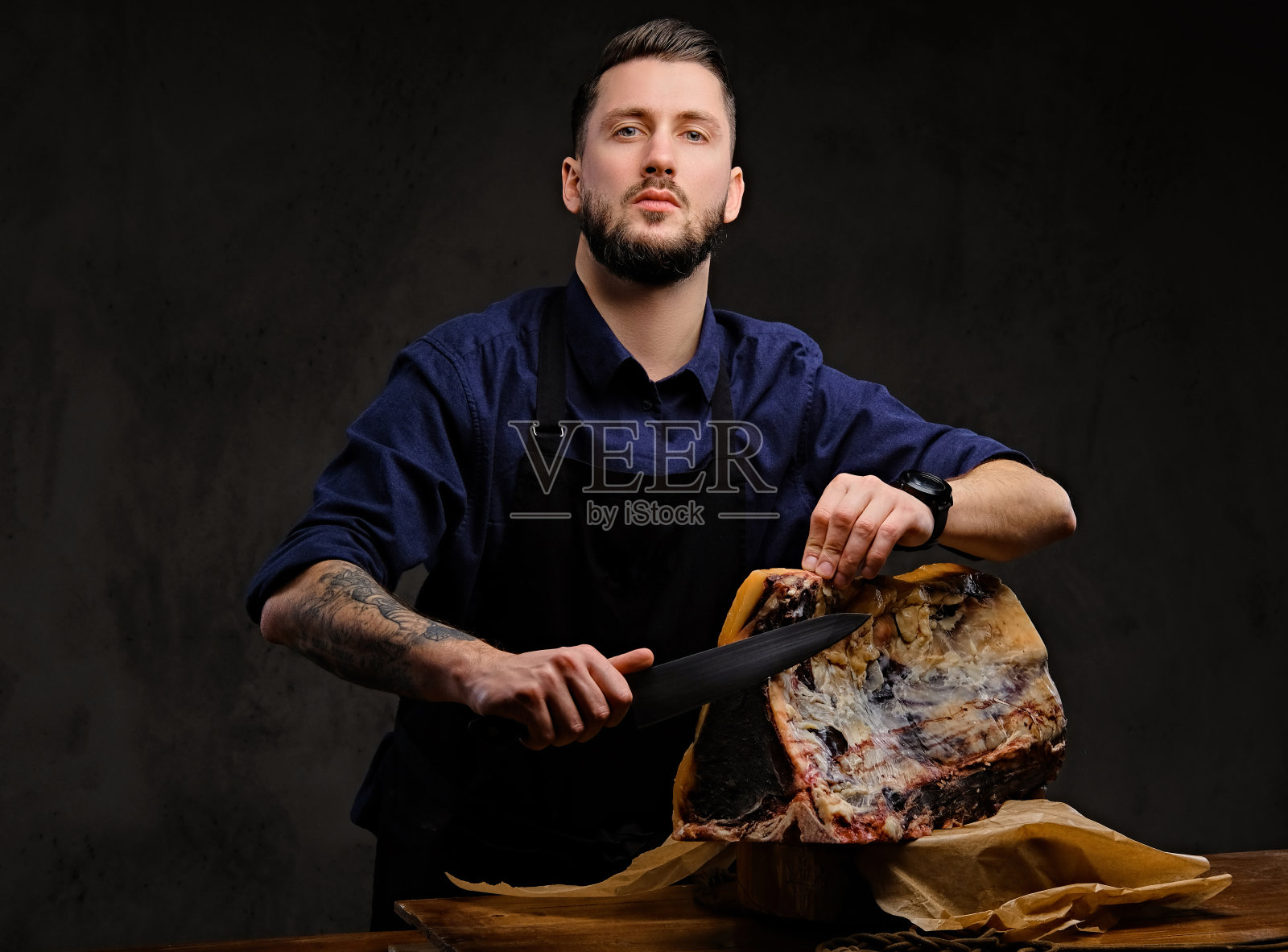 厨师厨师切独家牛肉干在一个狩猎房子的桌子上在黑暗的背景。照片摄影图片