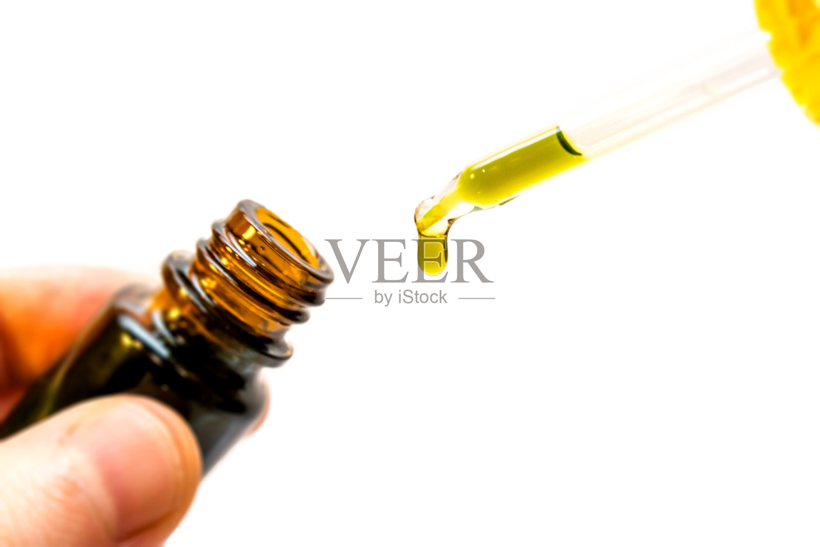 手握大麻油瓶，用吸管隔离照片摄影图片