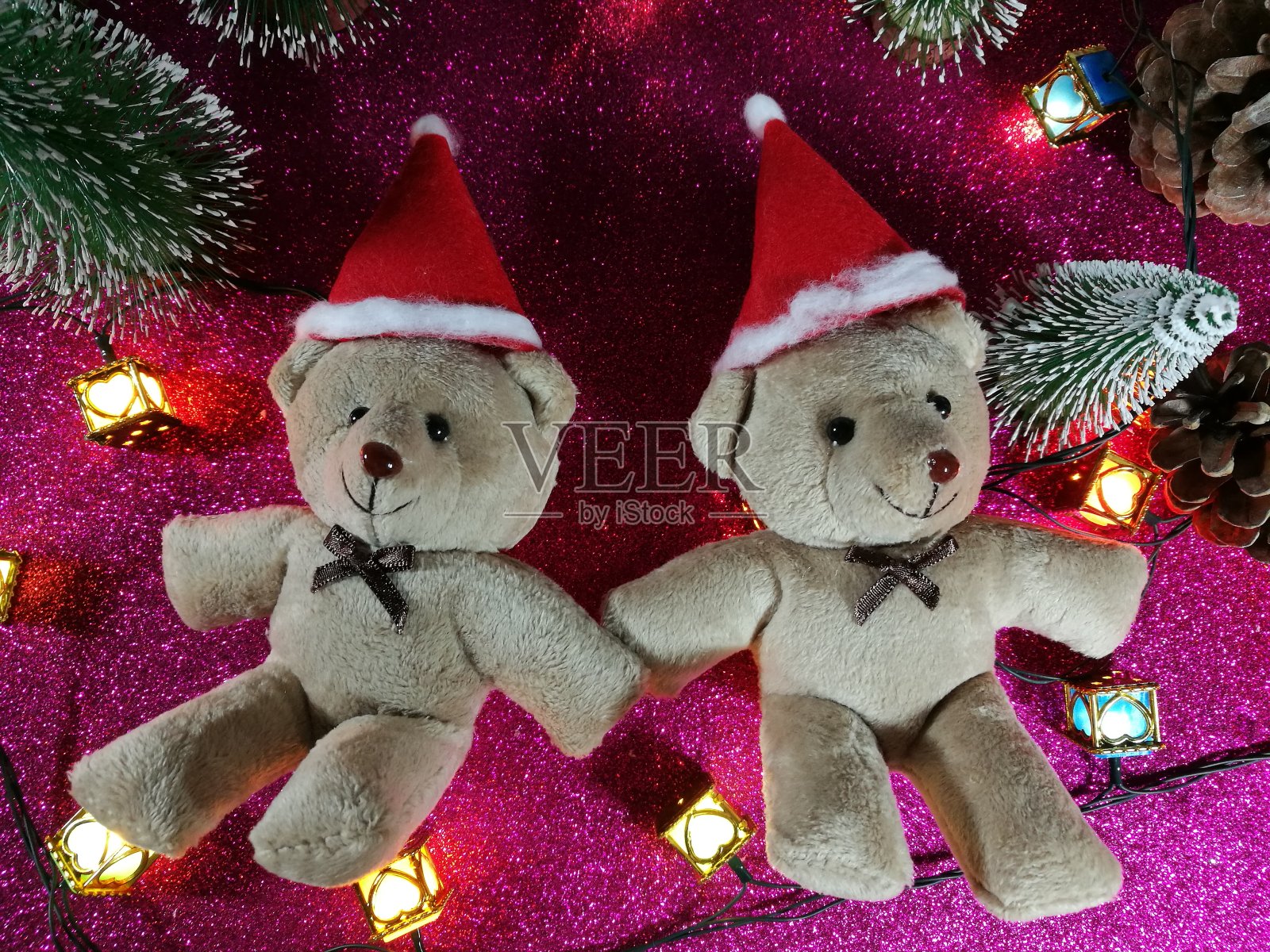 可爱的夫妇小熊平躺在粉色闪闪发光的背景附近装饰灯泡在平安夜，圣夜，圣诞快乐和新年快乐。照片摄影图片