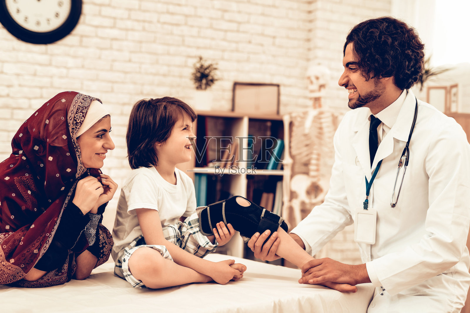 阿拉伯男医生包扎儿童腿部受伤照片摄影图片
