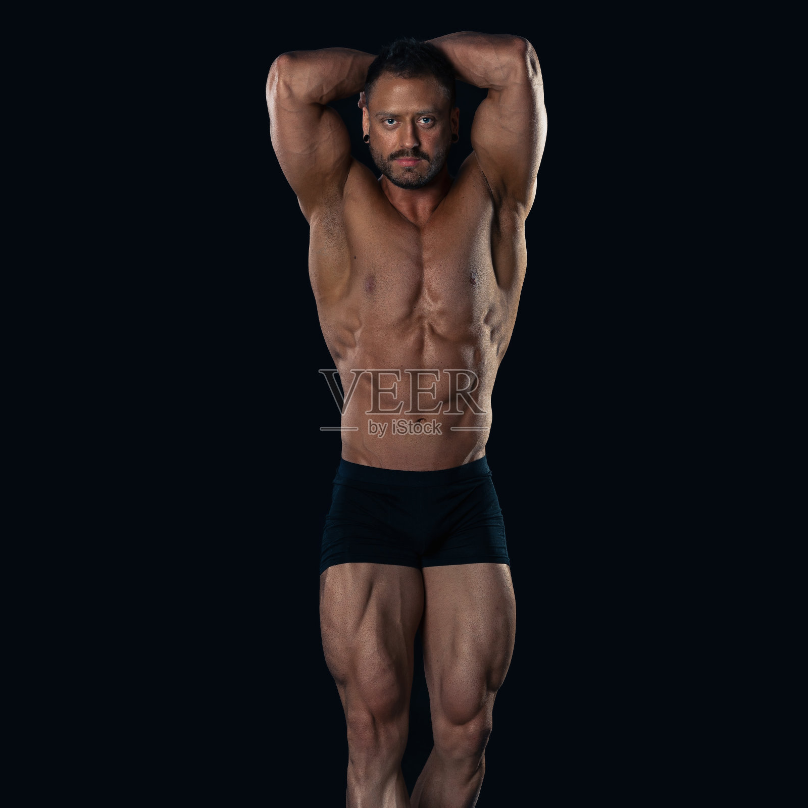 野蛮强壮的健美运动员在黑色背景下摆姿势。照片摄影图片