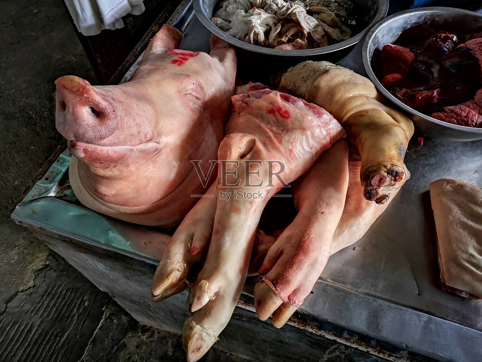 在泰国一个典型的新鲜湿肉市场里的猪头和猪肉。照片摄影图片