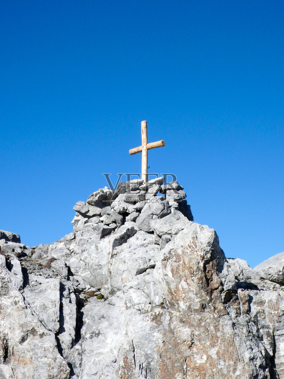 孤立的木顶横在一个尖利和锯齿状的山峰下，蓝天照片摄影图片