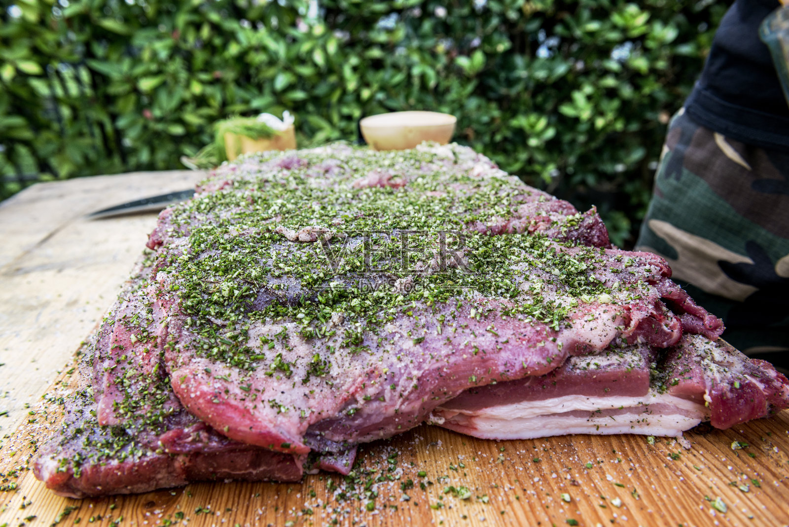 屠夫在卷猪肉时用盐和香草给肉调味照片摄影图片