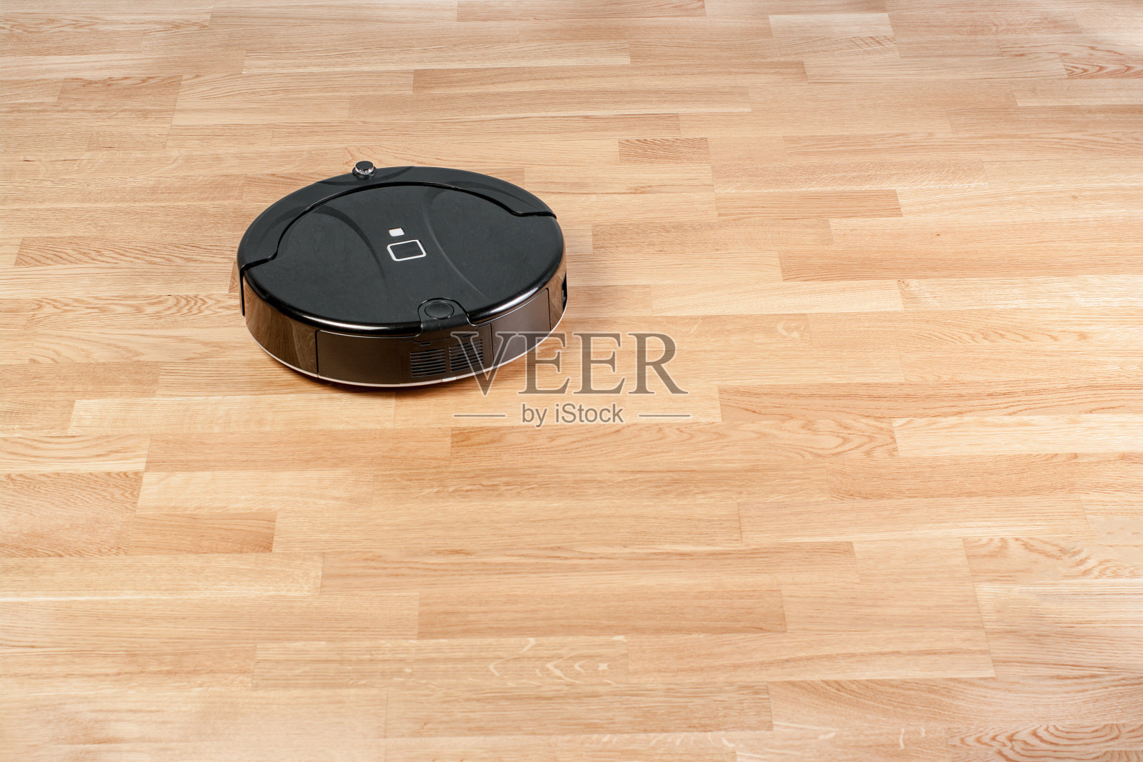 黑色机器人真空吸尘器在强化地板上运行。现代智能家政清洁技术。与你的位置为文本照片摄影图片