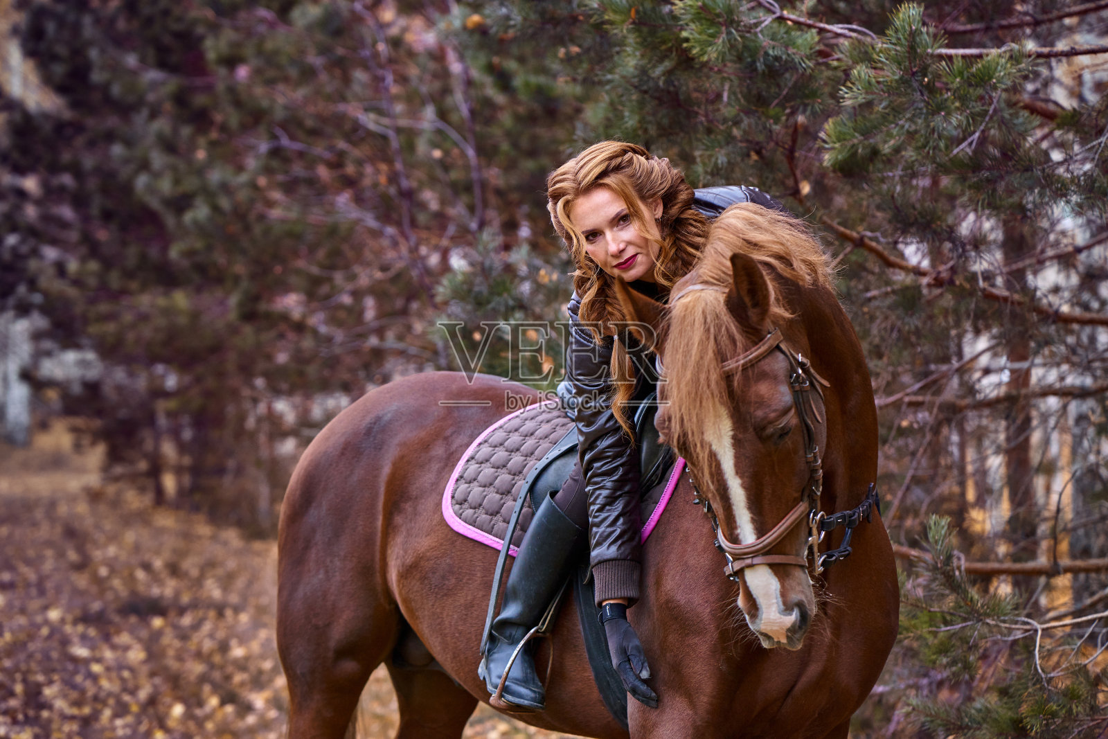 一位年轻漂亮的棕色长发女子的肖像。一个骑马的女人在森林里散步。照片摄影图片