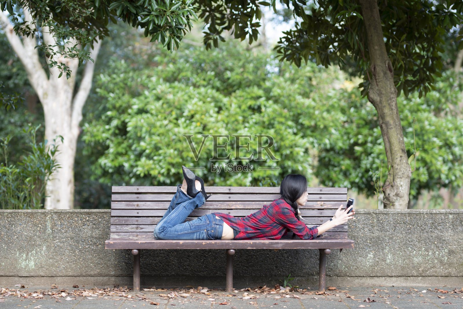 女人可以在公园的长椅上操作智能手机照片摄影图片
