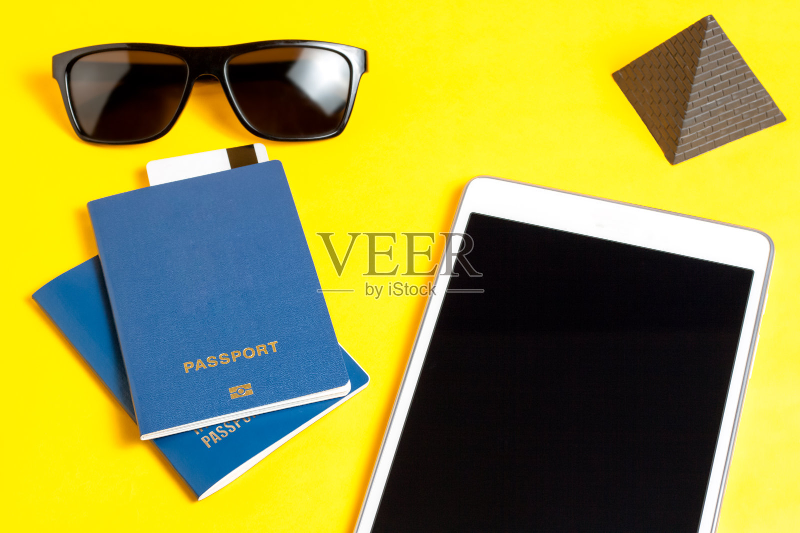 休闲旅游的概念。生物识别护照，太阳镜和亮黄色背景的旅行者用品照片摄影图片