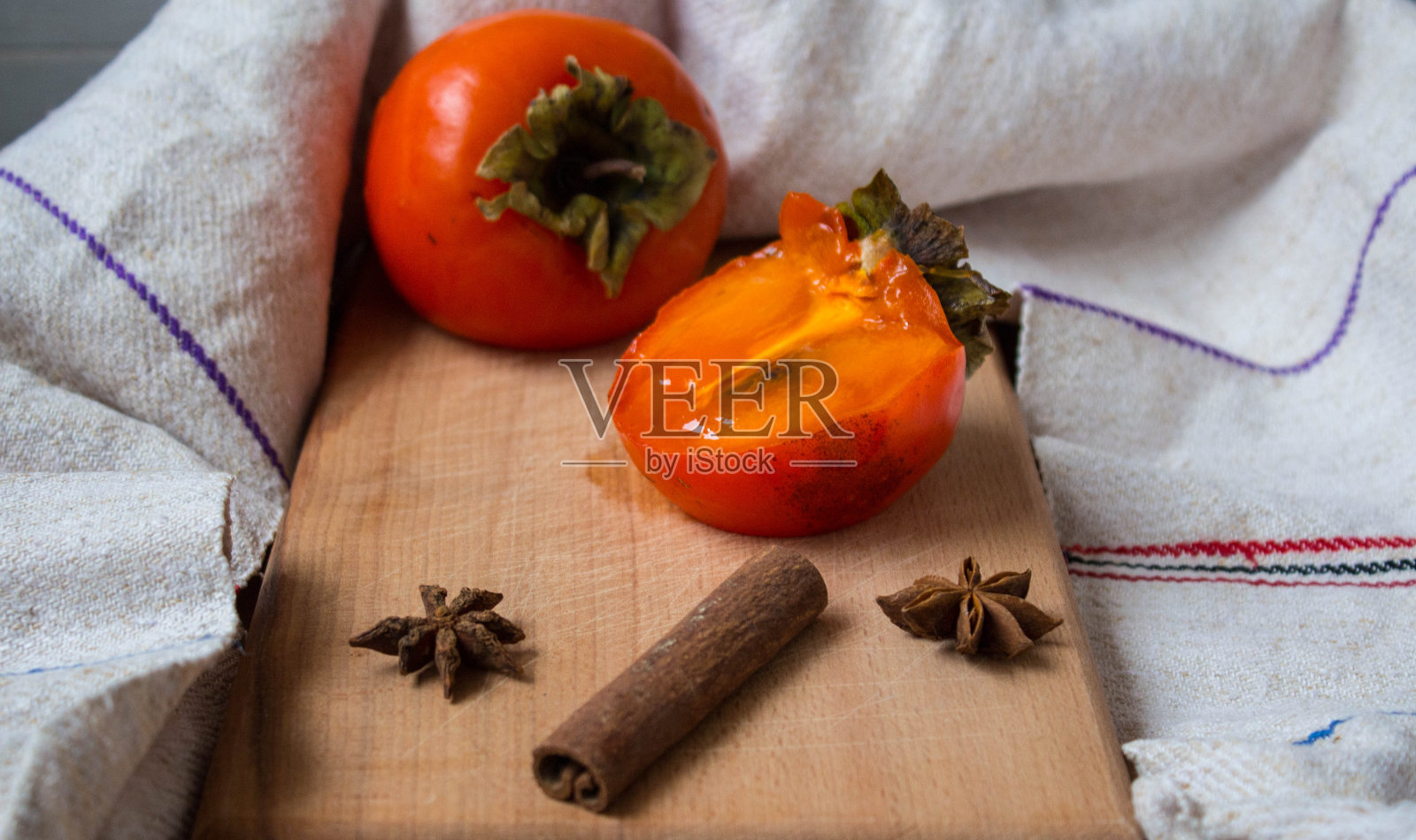 一个成熟的柿子与缟玛瑙和肉桂在木制甲板上照片摄影图片