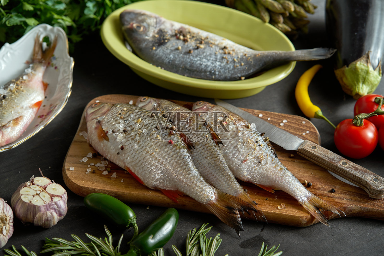 各式新鲜生鱼料理组合，配黑桌蔬菜照片摄影图片