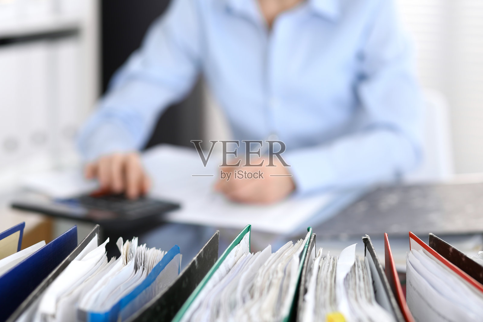 装着文件的活页夹正等着被处理，女商人或秘书的背影模糊不清。照片摄影图片