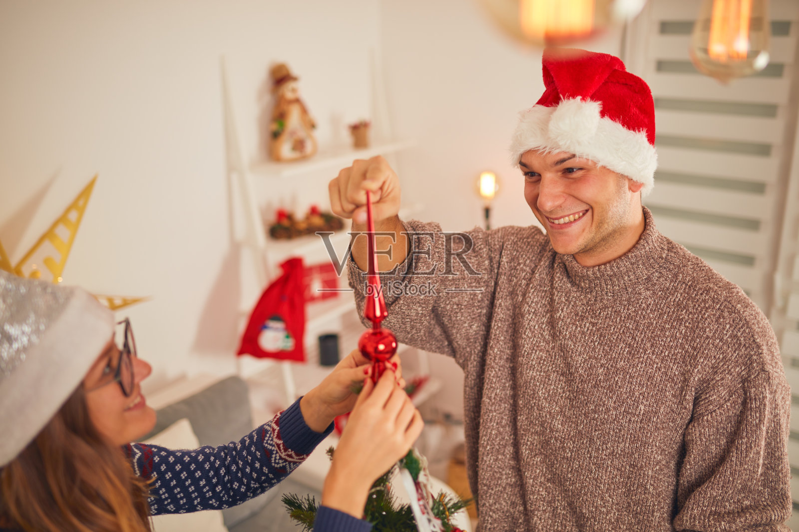 快乐的夫妇装饰圣诞树为新年/平安夜。照片摄影图片