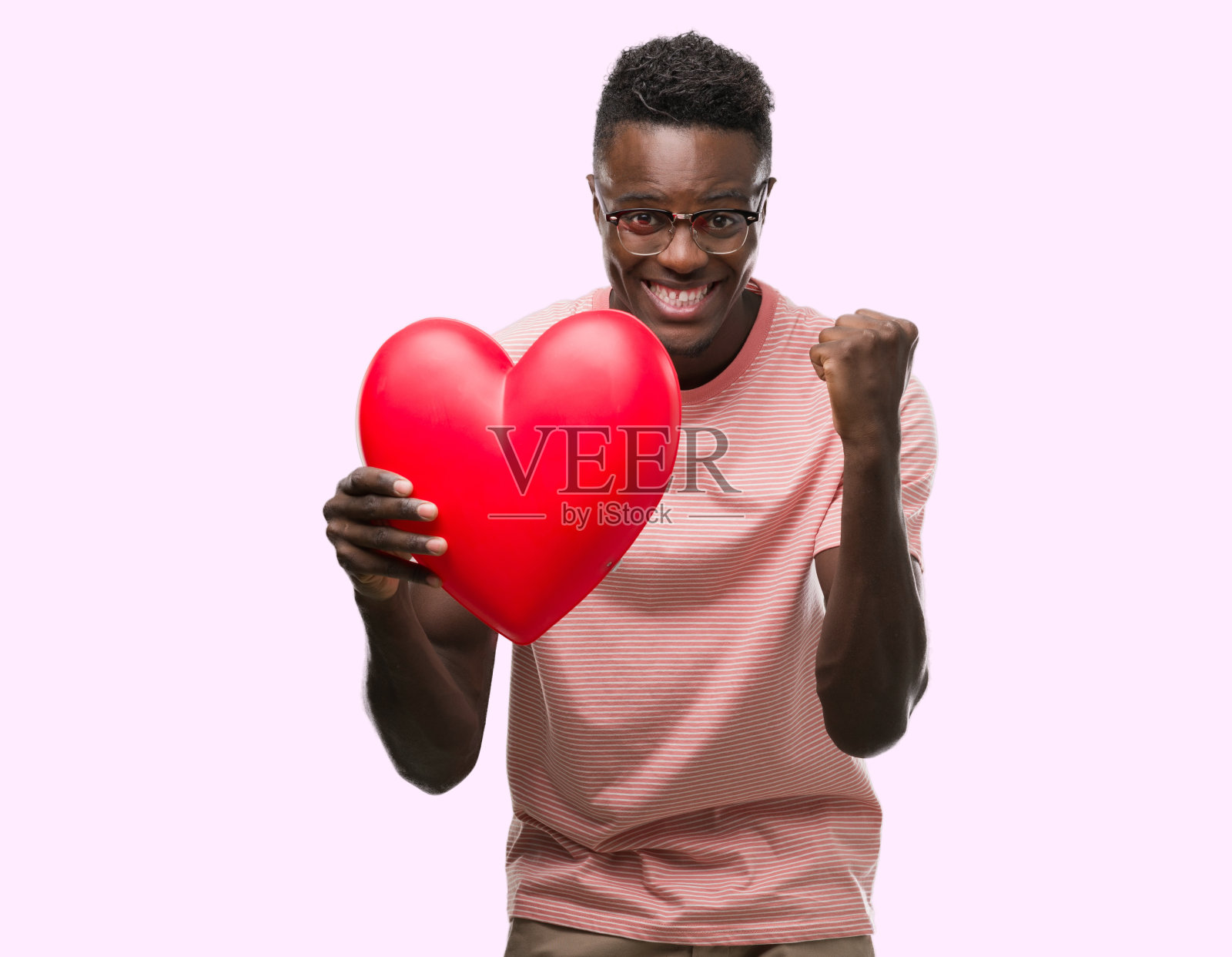 年轻的非洲裔美国人捧着一颗红红的心尖叫着，骄傲地庆祝胜利和成功，非常激动，欢呼的情绪照片摄影图片