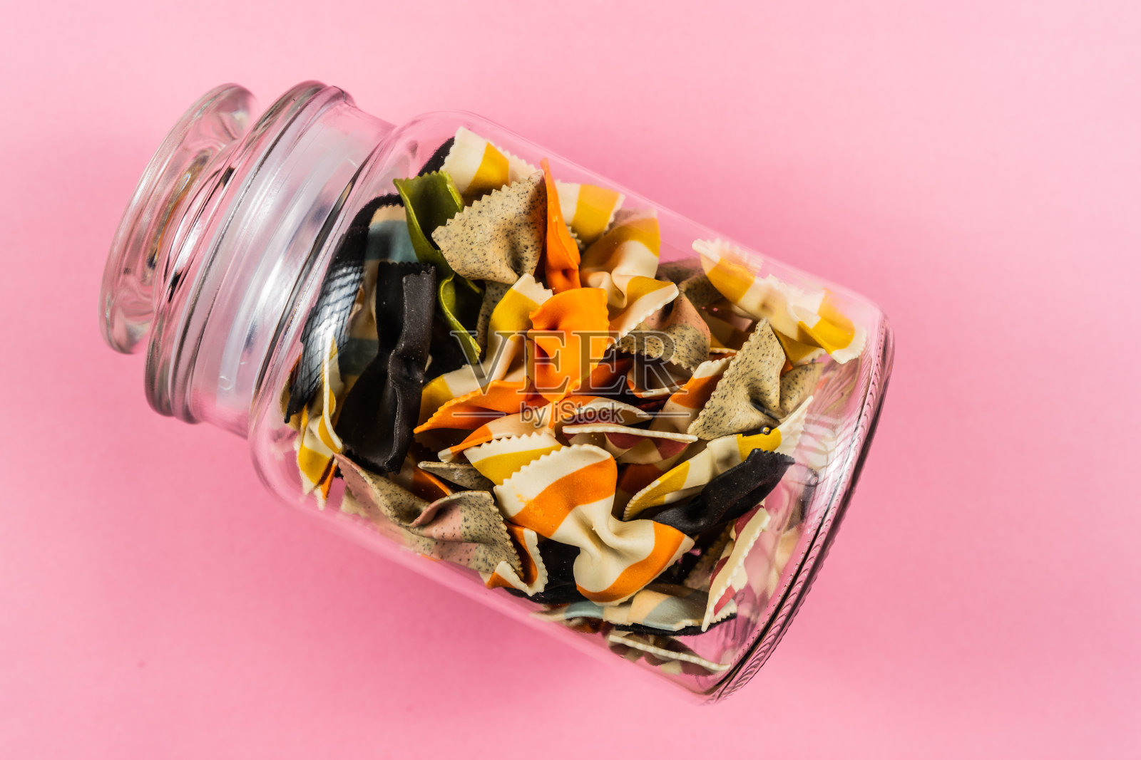 彩色的意大利面在玻璃罐上粉红色的背景照片摄影图片