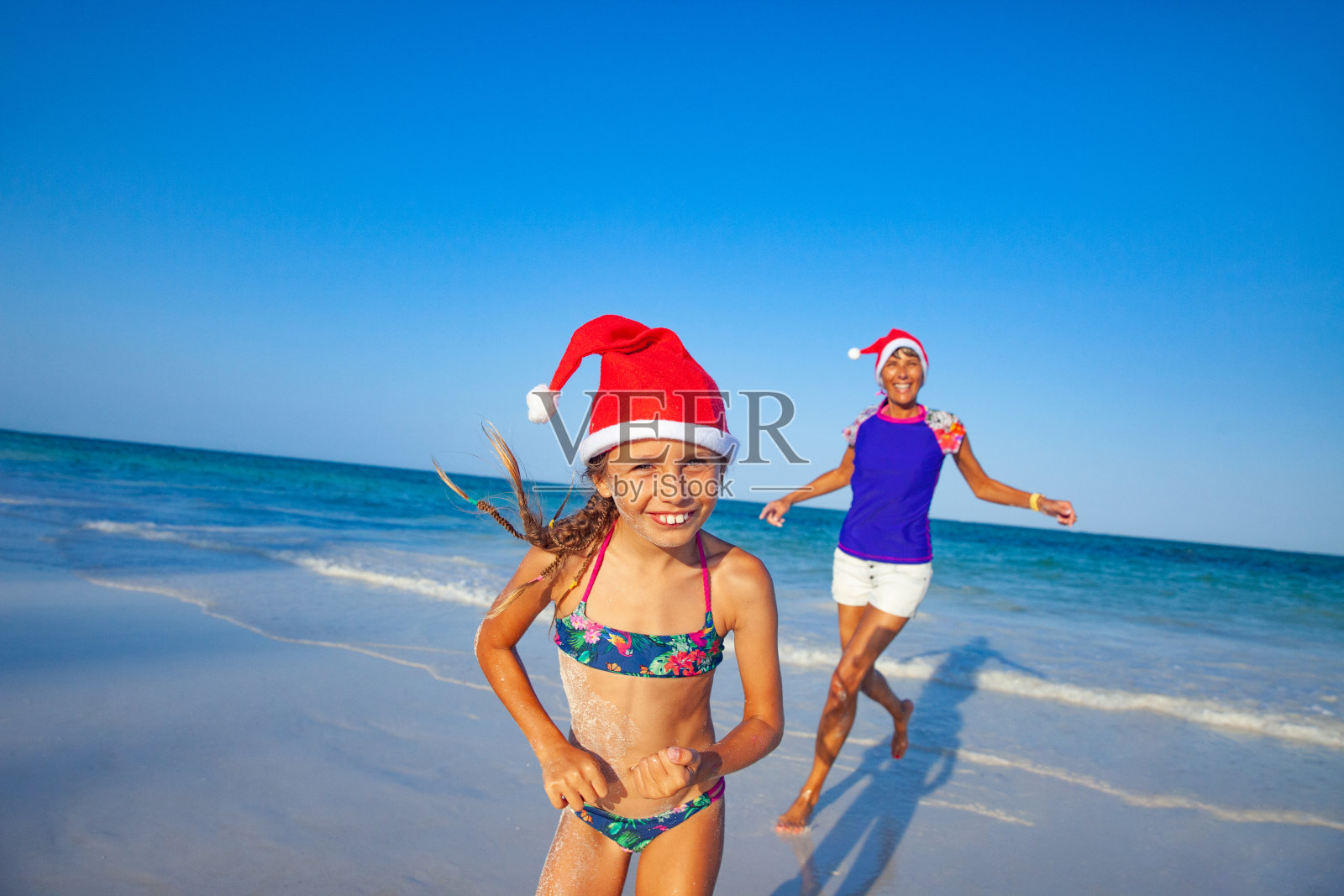 兴奋的小女孩在热带海滩上跑步在圣诞节假期照片摄影图片