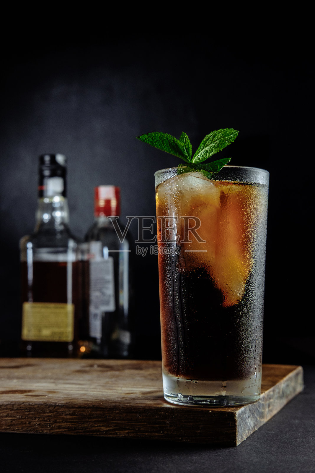 一杯可乐加冰，薄荷和迷迭香在黑色背景照片摄影图片