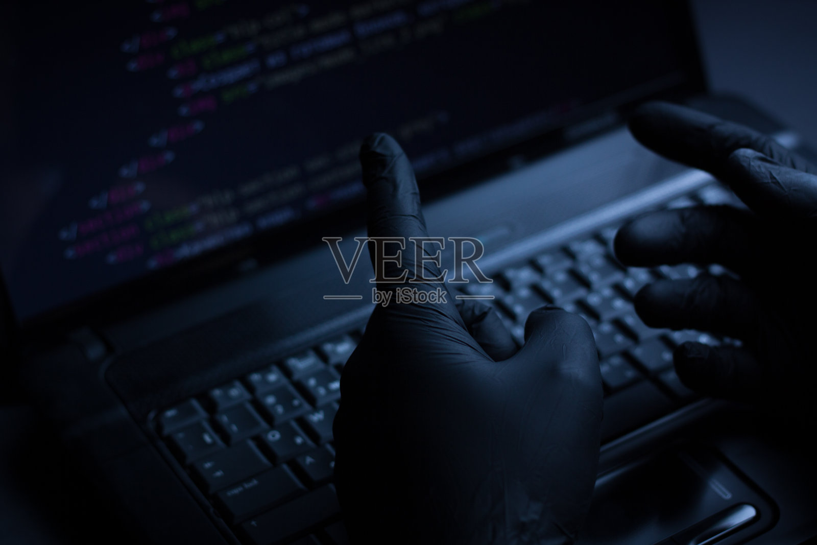 互联网黑客小偷概念。黑客利用笔记本电脑攻击电脑设备。黑暗而可怕的灯光。电脑屏幕上有很多符号。有选择性的重点。照片摄影图片