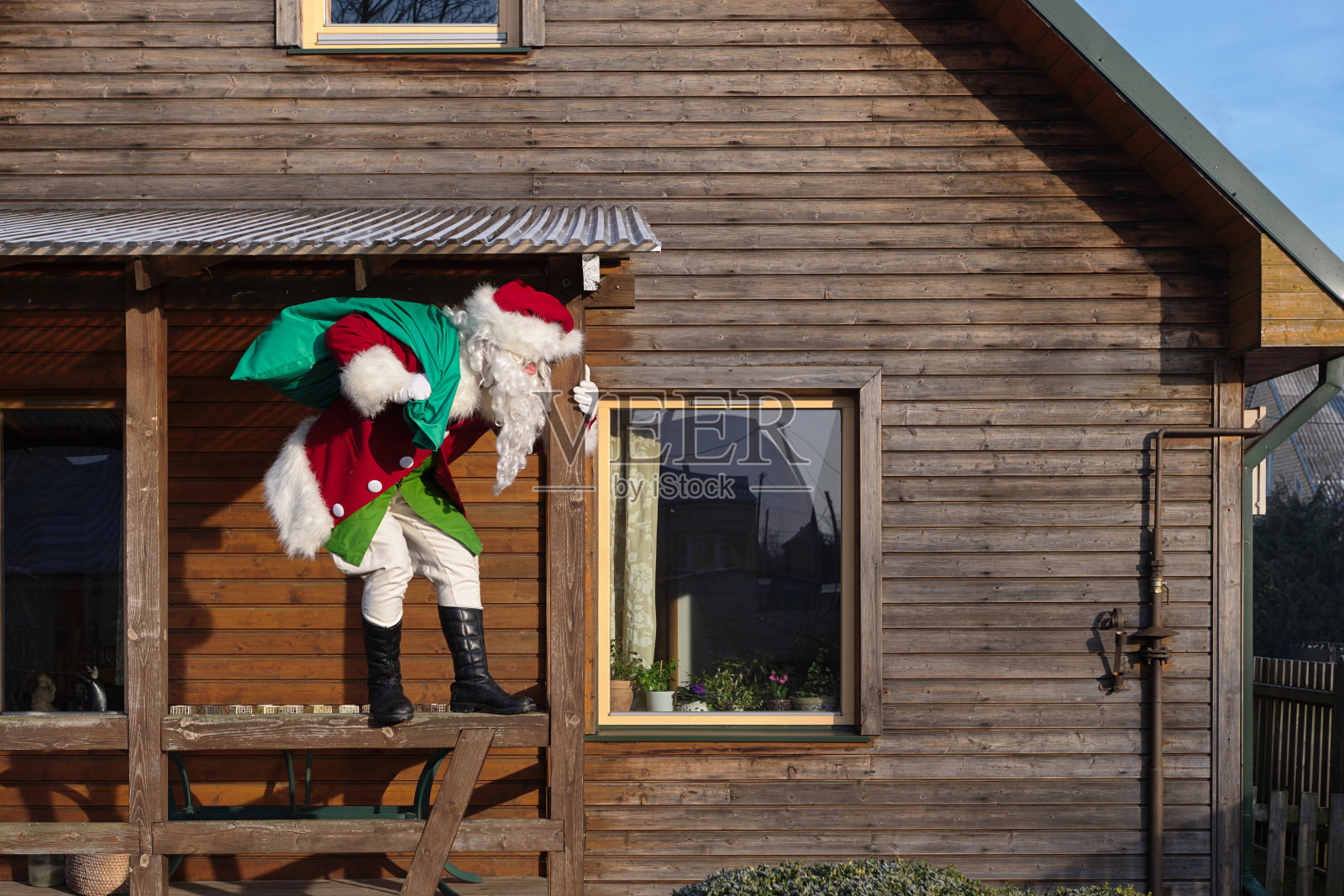 圣诞老人从房子的窗户飞进来。照片摄影图片