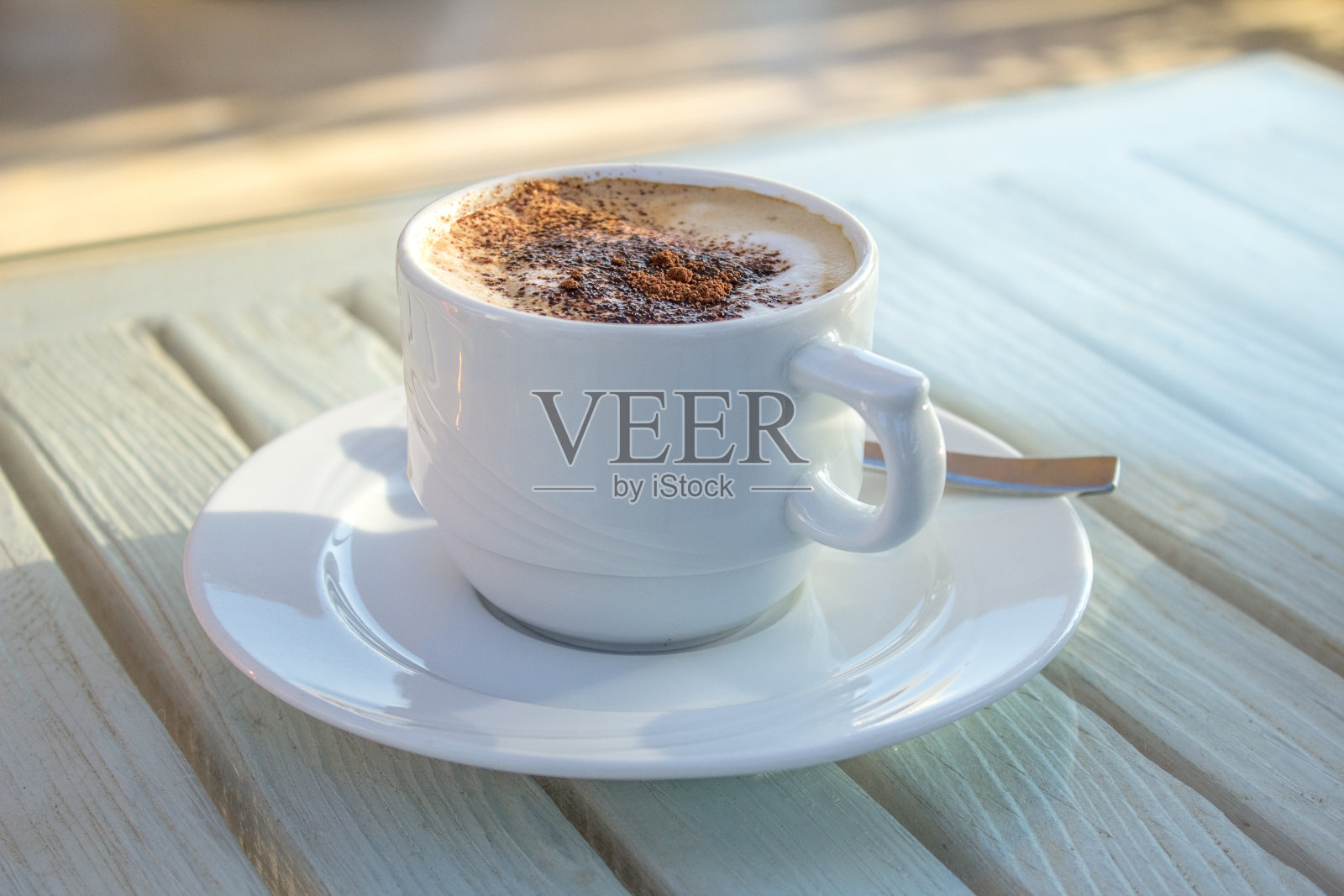 白色木桌上放着一杯卡布奇诺和豆蔻拉花咖啡照片摄影图片