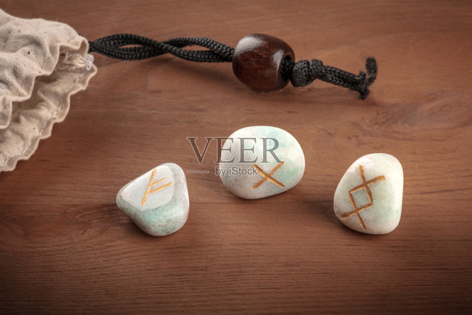 这是一个来自Futhark字母表的古斯堪的纳维亚符文的特写，石头上有用于巫术和其他魔法和占卜的符号，从一个袋子里扔出来，在一个黑色的背景上有一个地方写文字照片摄影图片