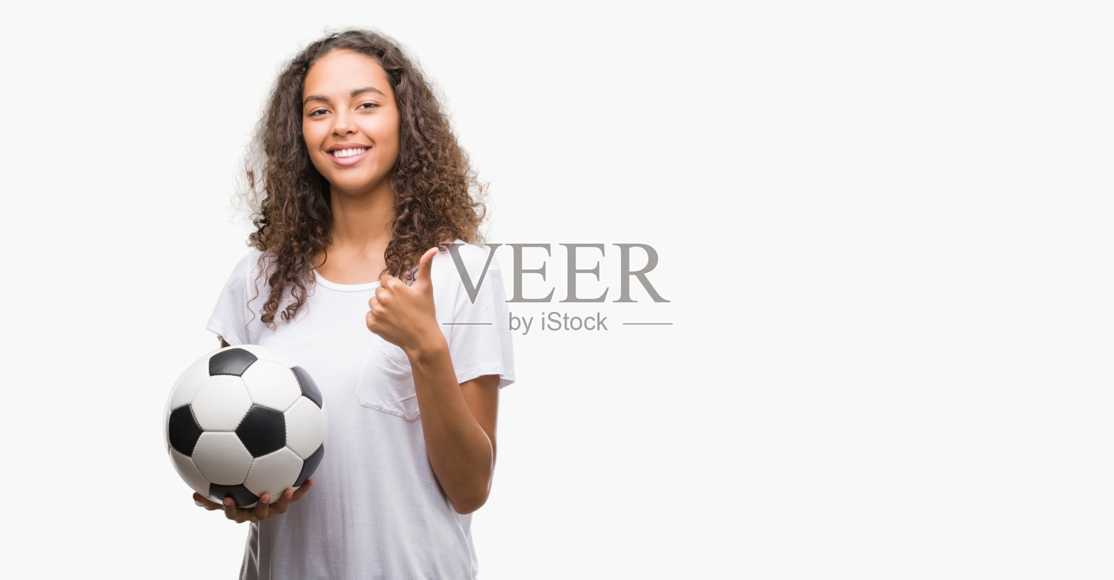 年轻的西班牙妇女拿着足球足球高兴与大微笑做ok的手势，拇指向上的手指，优秀的手势照片摄影图片